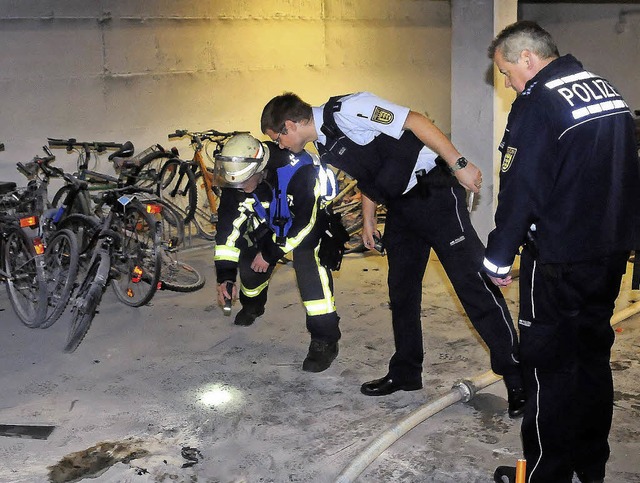Ein Feuerwehrmann und Polizeibeamte sichten die Spuren in der Tiefgarage.  | Foto: Wolfgang Knstle