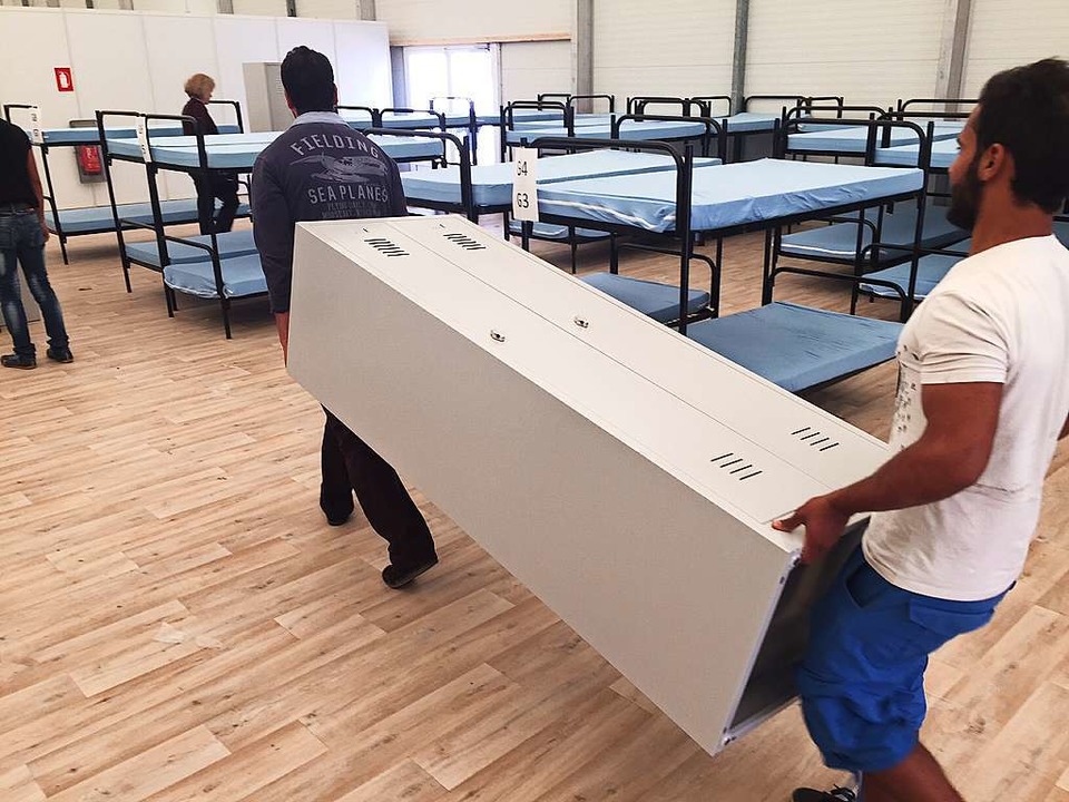 Asylbewerber aus Mannheim bauen die letzten Betten auf und tragen Schränke.   | Foto: Adrian Hoffmann