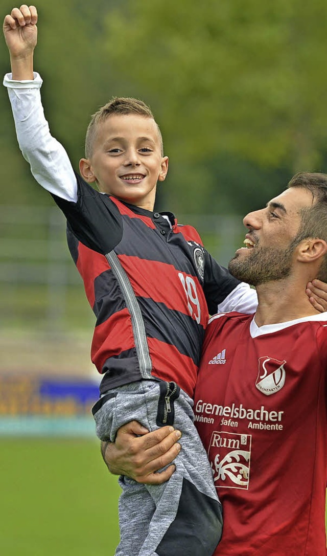 Mit dem Sohnemann auf dem Arm feiert SVK-Spielertrainer Maxhun Haxhija den Sieg.  | Foto: Thoma
