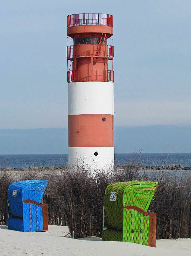 Ein rot-wei gestreifter Leuchtturm, ein blauer und ein grner Strandkorb ergeben ein farbenfrohes Foto an einem einsamen Strand auf Norderney. Dieses Postkartenmotiv stammt von  Dagmar Hitzfeld.