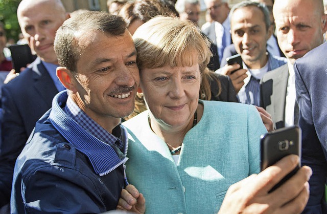 Selfie mit der Kanzlerin: Ein Flchtli...iert sich mit Angela Merkel in Berlin.  | Foto: dpa
