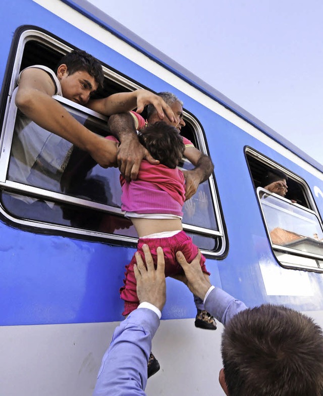 Im Bahnhof der kroatischen Stadt Beli ..., wird ein Kind in einen Zug gehievt.   | Foto: dpa