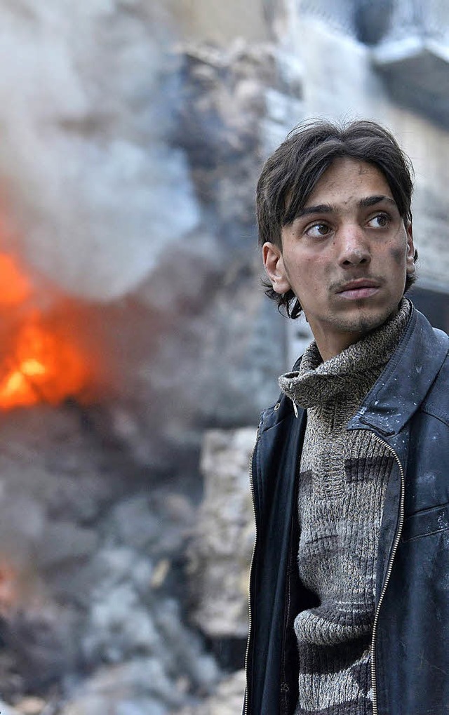 Syrer vor den Trmmern eines brennenden Hauses   | Foto: DPA