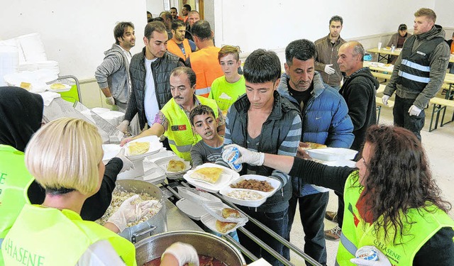 Die Flchtlinge nehmen in der Notunter...anisiert die Essensausgabe abwickeln.   | Foto: Roger Mller