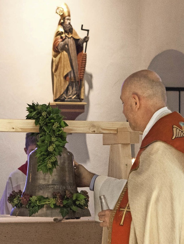 Pfarrer Heinz Vogel weiht die Glocke und reibt sie dazu mit Chrisam ein.   | Foto: Gabriele Zahn