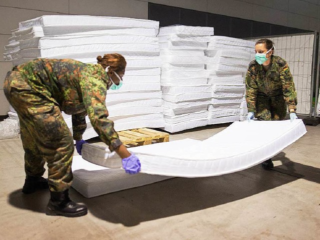 Soldaten der Bundeswehr bauen in einer...gart ein Feldbett fr Flchtlinge auf.  | Foto: dpa