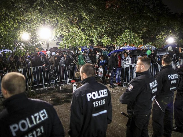 Polizisten sichern das Gelnde rund um...en Flchtlinge auf ihre Registrierung.  | Foto: dpa/AFP