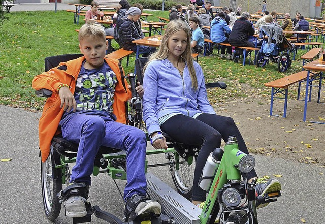 Zwei Kinder testen ein behindertengerechtes Fahrrad.  | Foto: Klinik