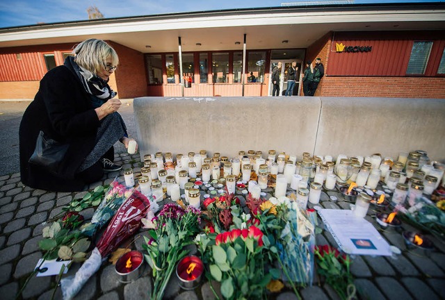 Eine Frau zndet vor der Schule in Tro...e Kerze zum Gedenken an die Opfer an.   | Foto: AFP