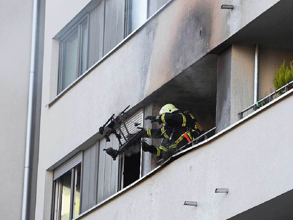 Feuerwehrleute warfen Gegenstnde aus der Wohnung ber das Balkongelnder.