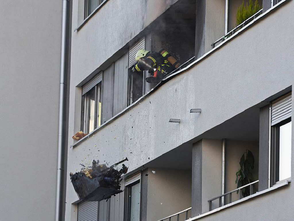 Feuerwehrleute warfen Gegenstnde aus der Wohnung ber das Balkongelnder.