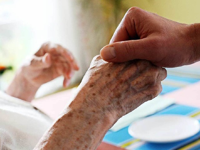 Ein Altenpfleger hlt in einem Pflegeheim die Hand einer Seniorin.  | Foto: dpa