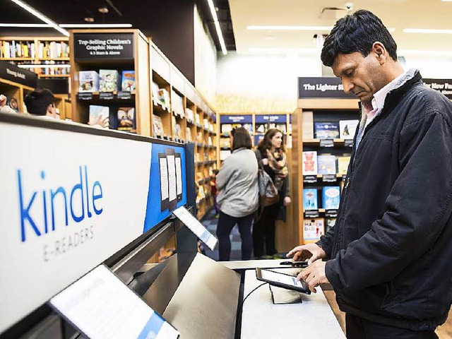 Ein Kunde probiert ein elektronisches Lesegert von Amazon im Laden aus.   | Foto: AFP