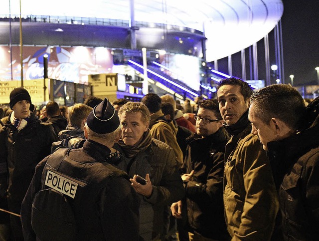 Schockierte Besucher diskutieren mit S...vor dem Stade de France die Situation.  | Foto: afp