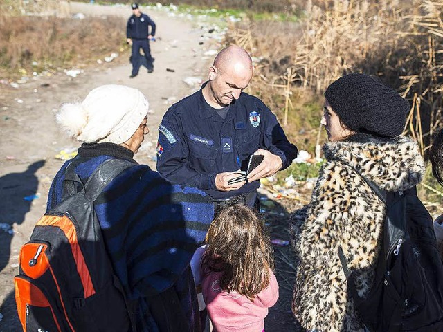 Ein serbischer Polizist kontrolliert die Psse von Flchtlingen.    | Foto: AFP