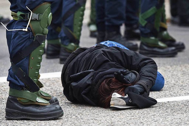 Eine Gegendemonstrantin liegt  in Wein...gs neben Polizeikrften auf dem Boden.  | Foto: dpa