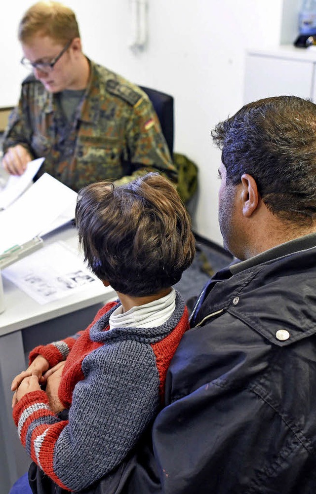 Ein Soldat stellt in Heidelberg Formul...eine syrische Flchtlingsfamilie aus.   | Foto: dpa