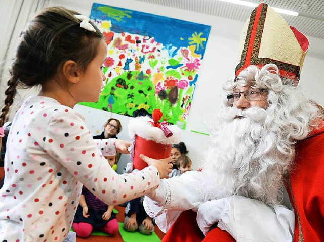 Der als Nikolaus verkleidete Rentner B...t Kindergartenkind Lilli ein Geschenk.  | Foto: dpa
