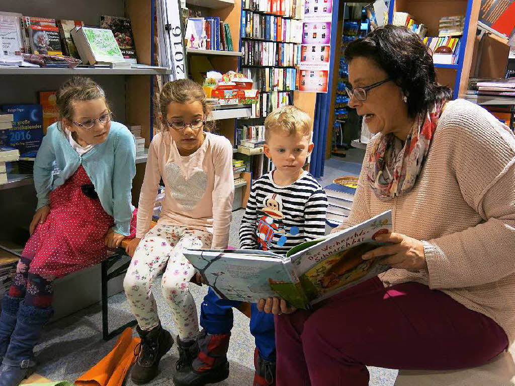 Lea, Johanna und Sven hren und schauen, was ihnen Susanne Spachholz aus dem Mrchenbuch vortrgt.