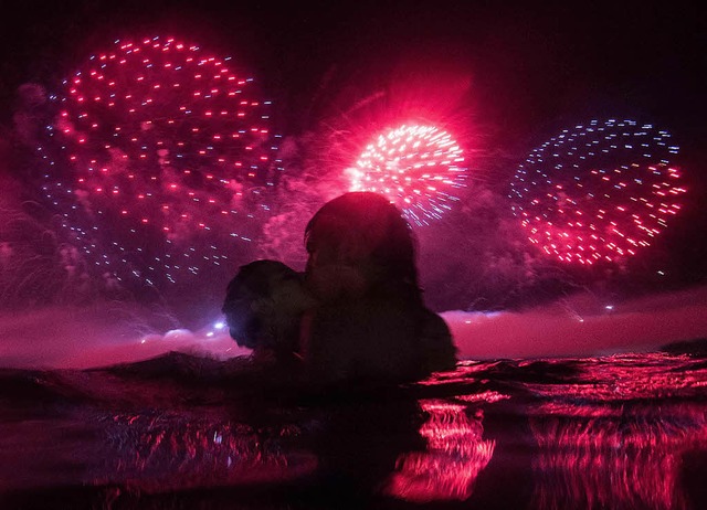 Unter dem Feuerwerk an der Copacabana ...hen im Wasser den Start ins neue Jahr.  | Foto: afp