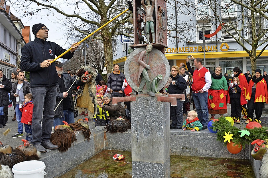Die Dinkelbergschrate, hier Vorsitzender Jürgen Zöhner mit Besen, staubten am Donnerstag ihre Masken am Narrenbrunnen ab. (Foto: Peter Gerigk) Die Dinkelbergschrate, hier Vorsitzender Jürgen Zöhner mit Besen, staubten am Donnerstag ihre Masken am Narrenbrunnen ab. (Foto: Peter Gerigk)