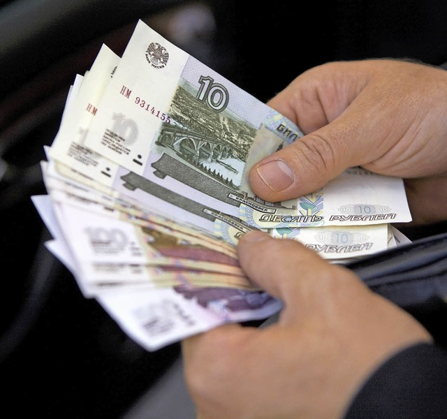 Ein Mann zhlt russische Rubel &#8211;...e Inflation das Geld stark entwertet.   | Foto: dpa