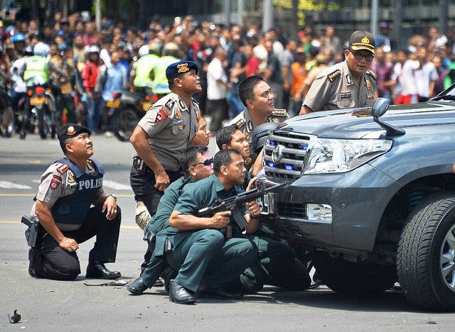 Polizisten verschanzen sich whrend de...m Hintergrund sammeln sich Neugierige.  | Foto: AFP
