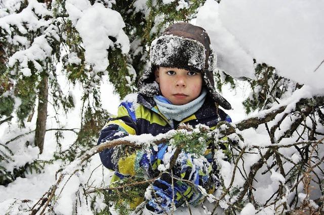 Kinder spielen mit Sachen, die Schnee und Wald gerade hergeben
