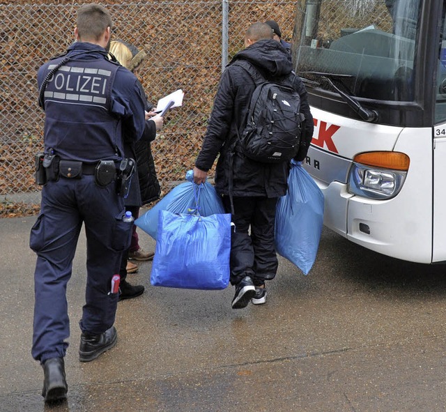 Ein Polizist begleitet in  Ellwangen einen Flchtling zu einem Bus.   | Foto: dpa