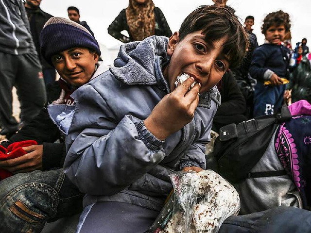 Syrische Flchtlingskinder werden an der Grenze mit Lebensmitteln versorgt.  | Foto: AFP