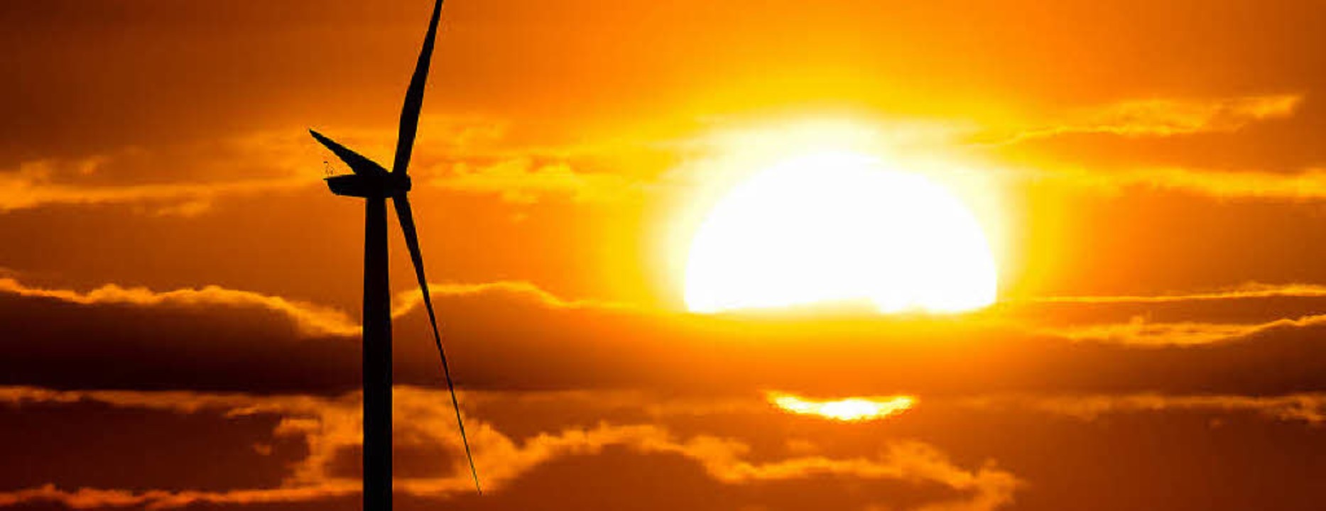 Die Silhouette eines Windrads in der Morgensonne im Januar  | Foto: dpa