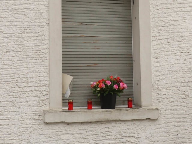 Menschen haben Blumen und Kerzen in ei...auses gestellt, in dem der Mann starb.  | Foto: Wilfried Dieckmann
