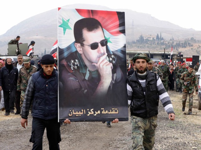 Untersttzer von Prsident Assad trage...ild des Diktators zu einer Kundgebung.  | Foto: AFP