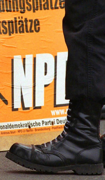 Mann mit Springerstiefeln vor einem NPD-Wahlplakat  | Foto: DPA