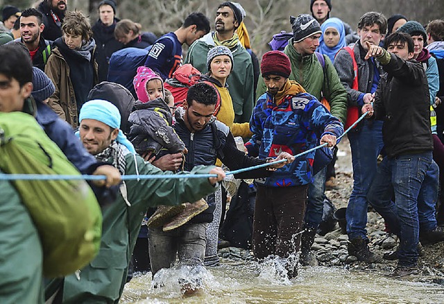 Flchtlinge queren einen Fluss.    | Foto: dpa