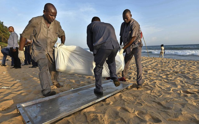 Am Strand von Grand Bassam tragen Helfer Leichen  weg.   | Foto: AFP