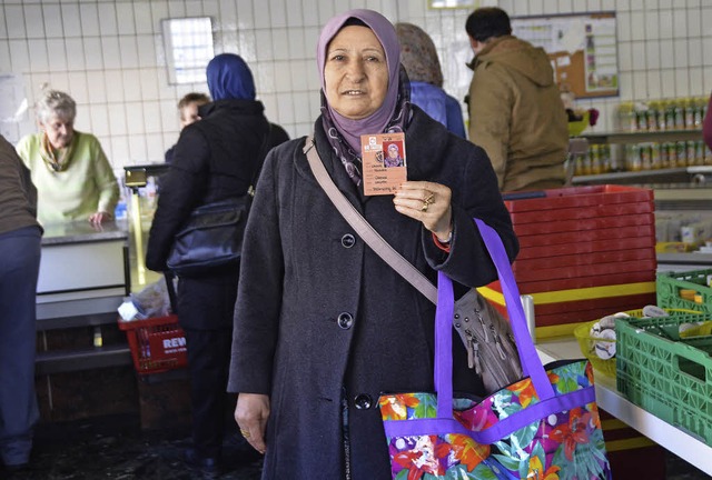 Eine Frau zeigt ihren neuen Berechtigungsschein fr den Einkauf im Tafelladen.  | Foto: Peter Gerigk