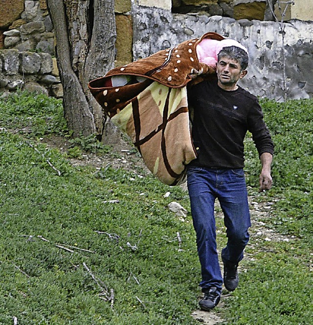 Ein Mann bringt sich mit seinen Habseligkeiten vor Kmpfen in Sicherheit.  | Foto: afp