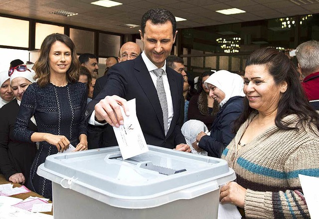 Syriens Prsident Baschar al-Assad bei...mmabgabe. Links steht seine Frau Asma.  | Foto: AFP