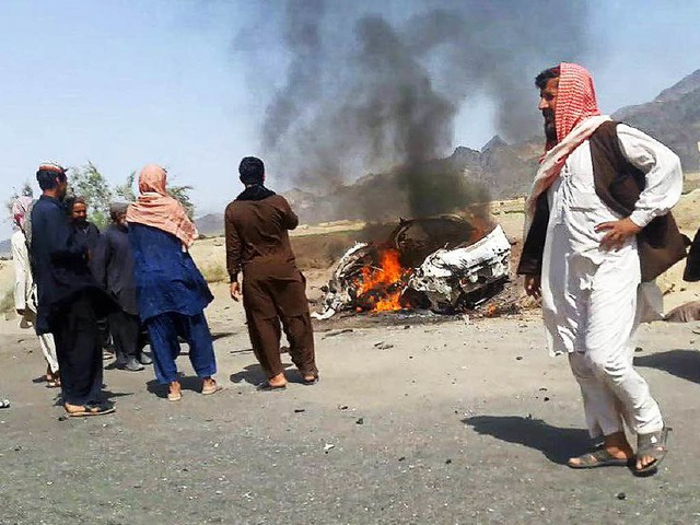 Mnner begutachten das brennende Auto,...offenbar Mullah Mansur gettet wurde.   | Foto: AFP