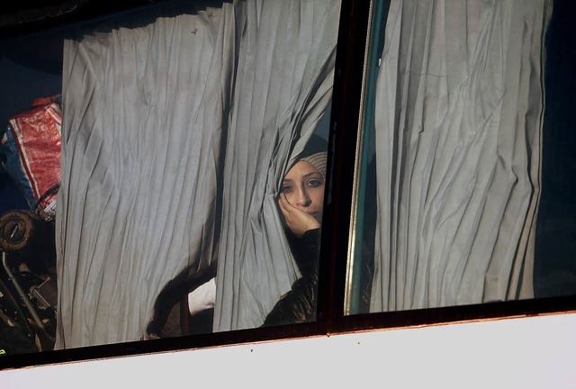 Eine Frau blickt  aus dem Bus, der sie...isierten Camp bei Idomeni wegbringt.    | Foto: afp