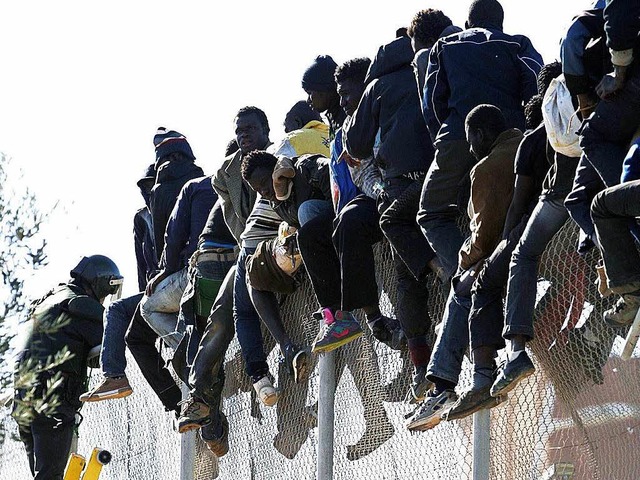 Flchtlinge sitzen auf einem Zaun zwischen Marokko und Melilla  | Foto: dpa
