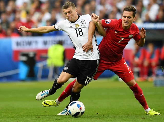 Bissiger Zweikampf: Toni Kroos wird von Arkadiusz Milik gestoppt.  | Foto: AFP