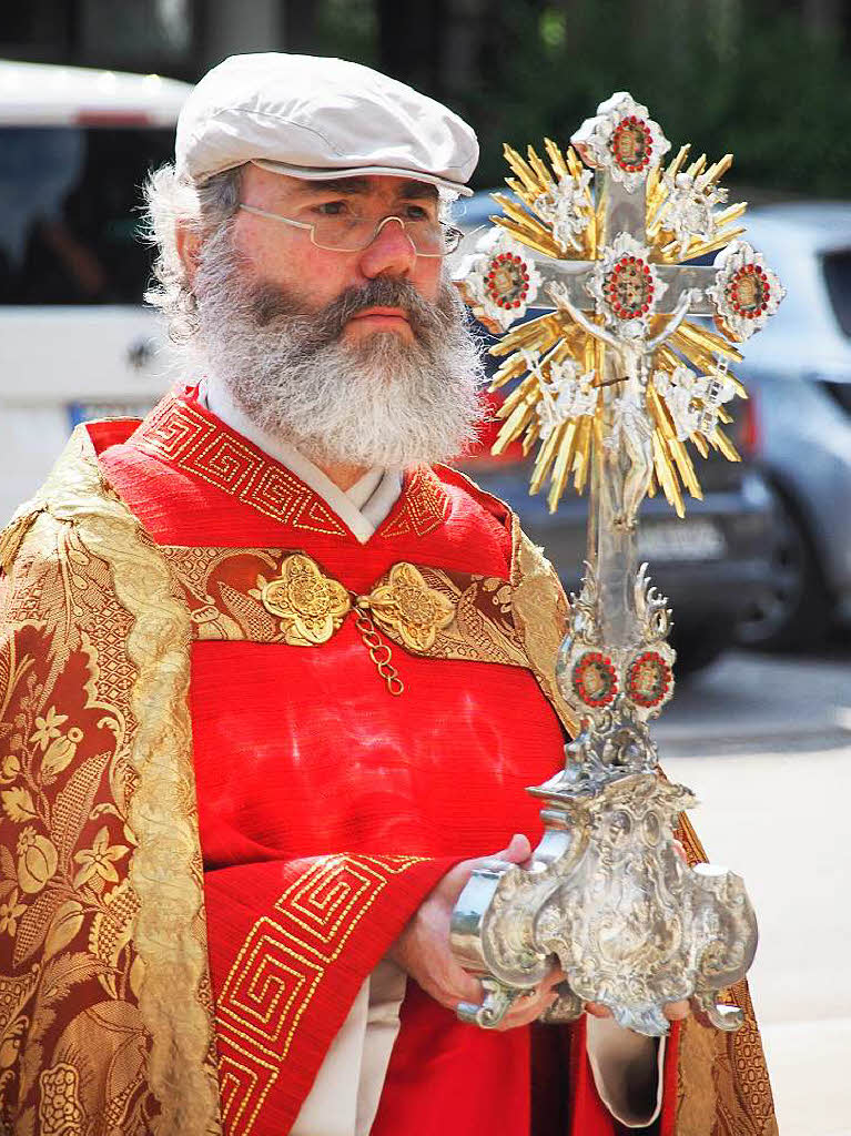 Pfarrer Klemens Armbruster mit Kreuz und Sonnenschutz.