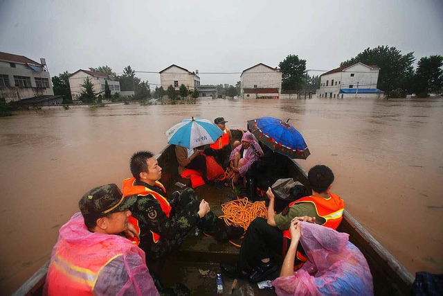 China: Menschen werden in Booten vor den Wasserfluten in Sicherheit  gebracht.  | Foto: AFP
