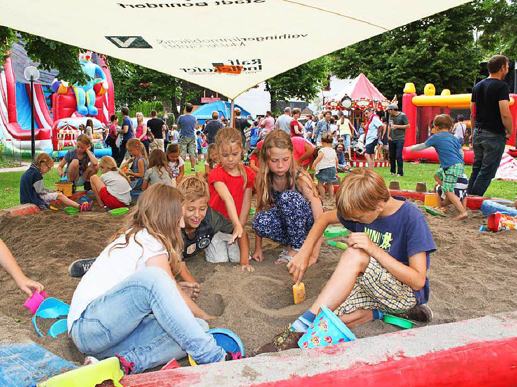 Selbstvergessen spielen diese Kinder im Riesensandkasten, whrend ihre Eltern beim Fest verweilen und plaudern.