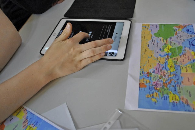 Schler mit Tablet und Weltkarte beim Geocache-Projekt.   | Foto: Diakonie