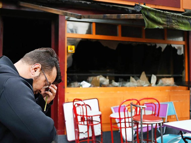 Ein Mann trauert in Rouen vor der ausgebrannten Bar.  | Foto: AFP