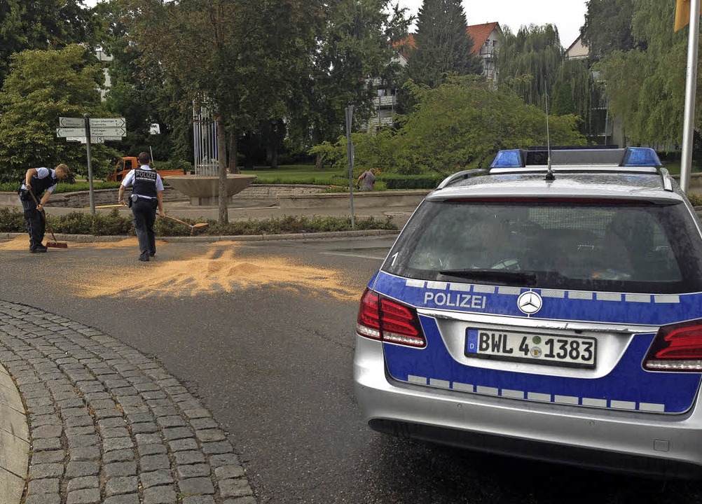 Polizeibeamte säubern die Fahrbahn des...rs und kehren das Saatguts zusammen.    | Foto: Markus Horn