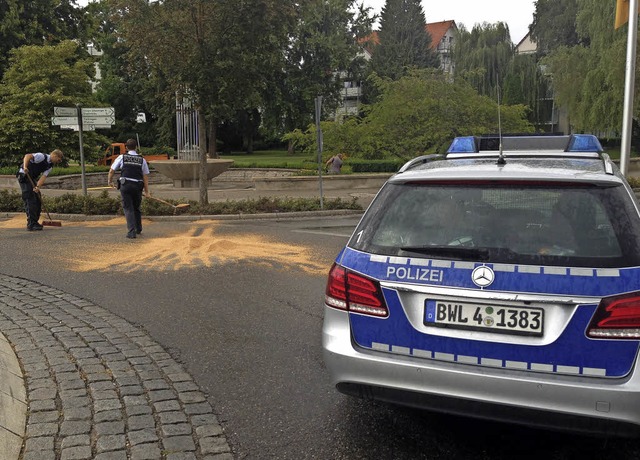 Polizeibeamte subern die Fahrbahn des...rs und kehren das Saatguts zusammen.    | Foto: Markus Horn